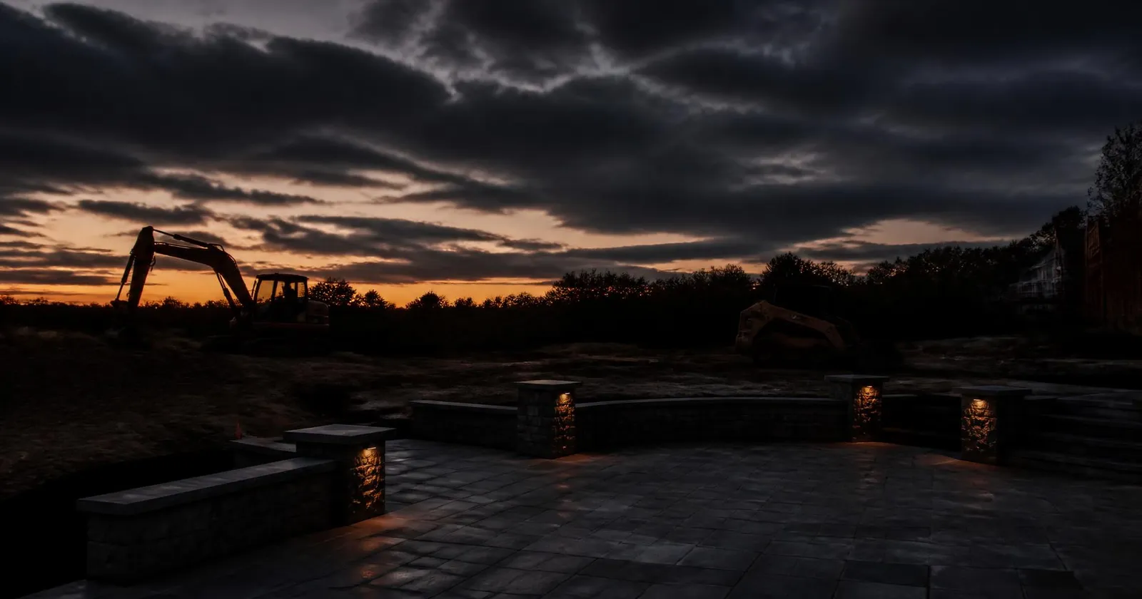 Landscape construction equipment on a Norfolk, MA job site at dusk